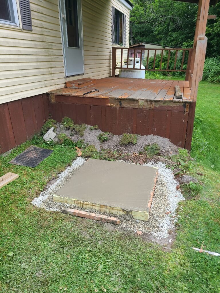 New concrete landing pad poured at the base of the deck stairs